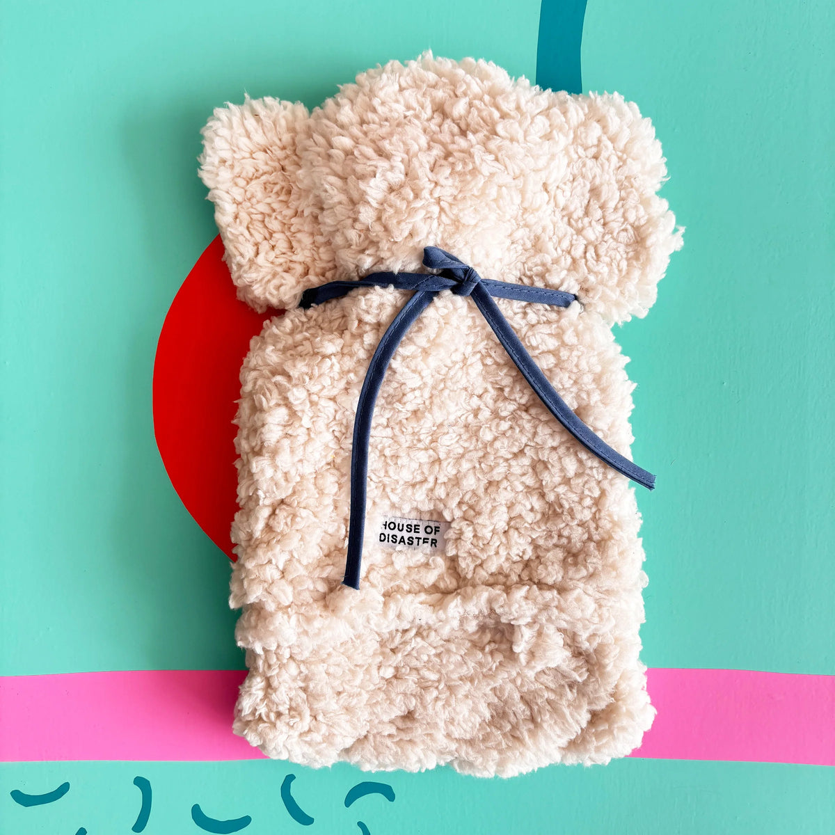 Back of fluffy dog hot water bottle tied with blue strap.