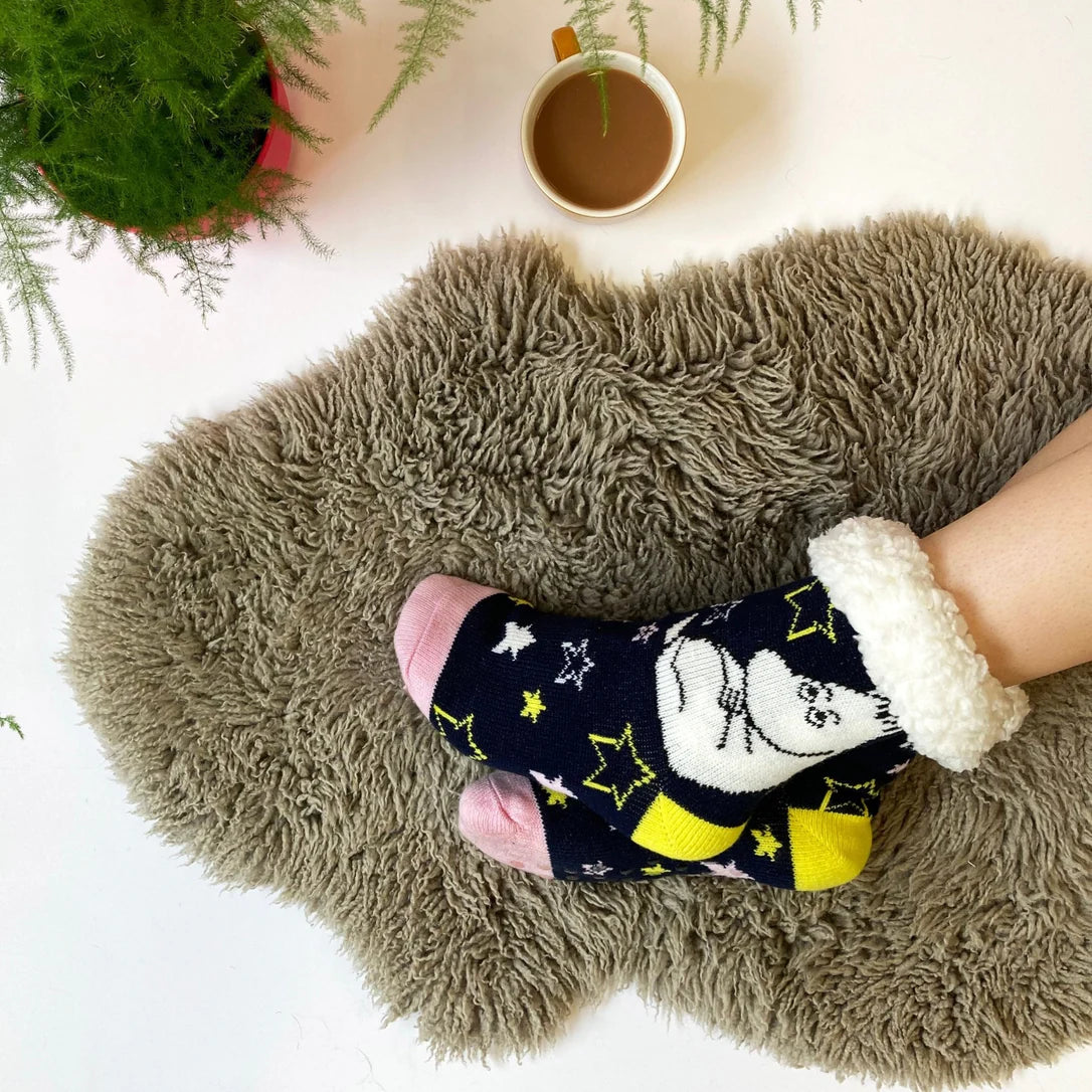 Moomin slipper socks worn on rug, showing star pattern and relaxed design