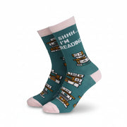 Pair of teal and pink bamboo socks with “Shhh… I’m Reading” text and book stack design, shown on angled display.