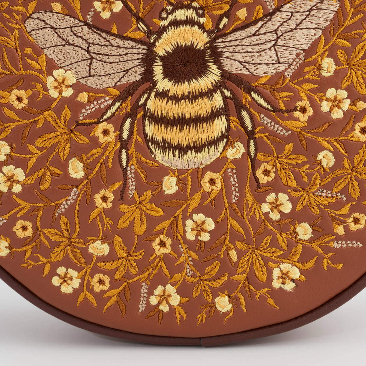 Detail of the gold embroidered bumble bee among honey coloured flowers