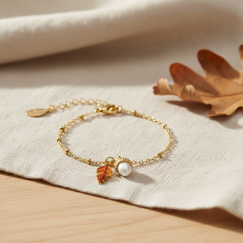 Bill Skinner Acorn and Oak Bracelet, gold chain with acorn and enamel leaf charm, on white