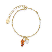 Bill Skinner Acorn and Oak Bracelet, gold chain with acorn and enamel leaf charm, on white