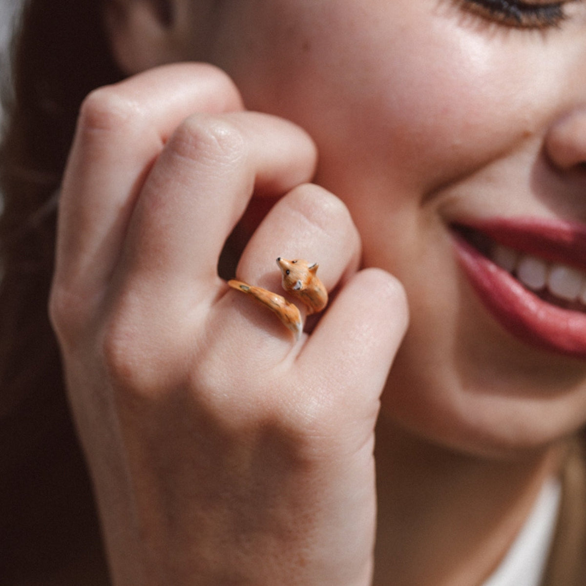 Fox Ring worn on a finger, close to a smiling face