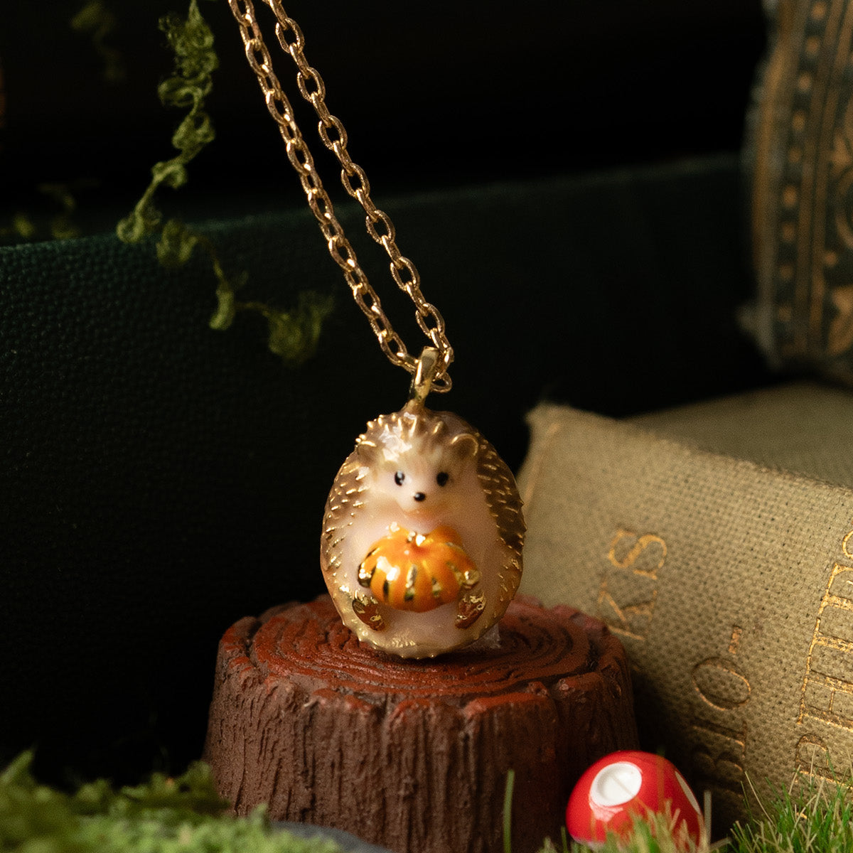 Close-up of the enamel hedgehog hugging a pumpkin, on a moss and toadstool scene