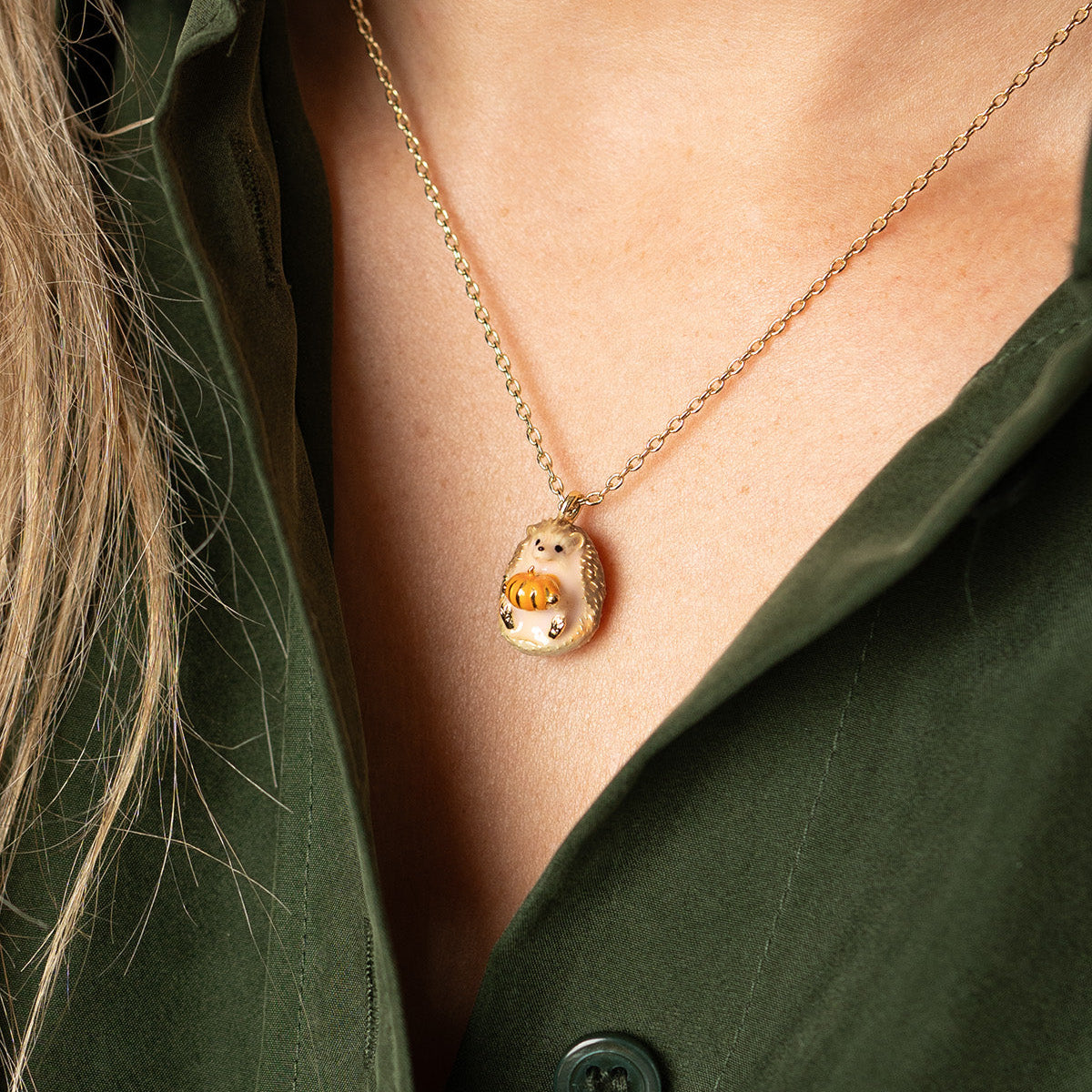 Hedgehog and Pumpkin Mini Pendant worn with a dark green shirt