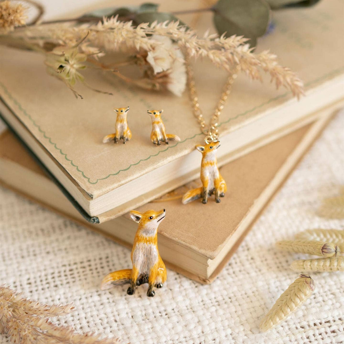 Fable enamel fox necklace styled with matching fox earrings and brooch on vintage books