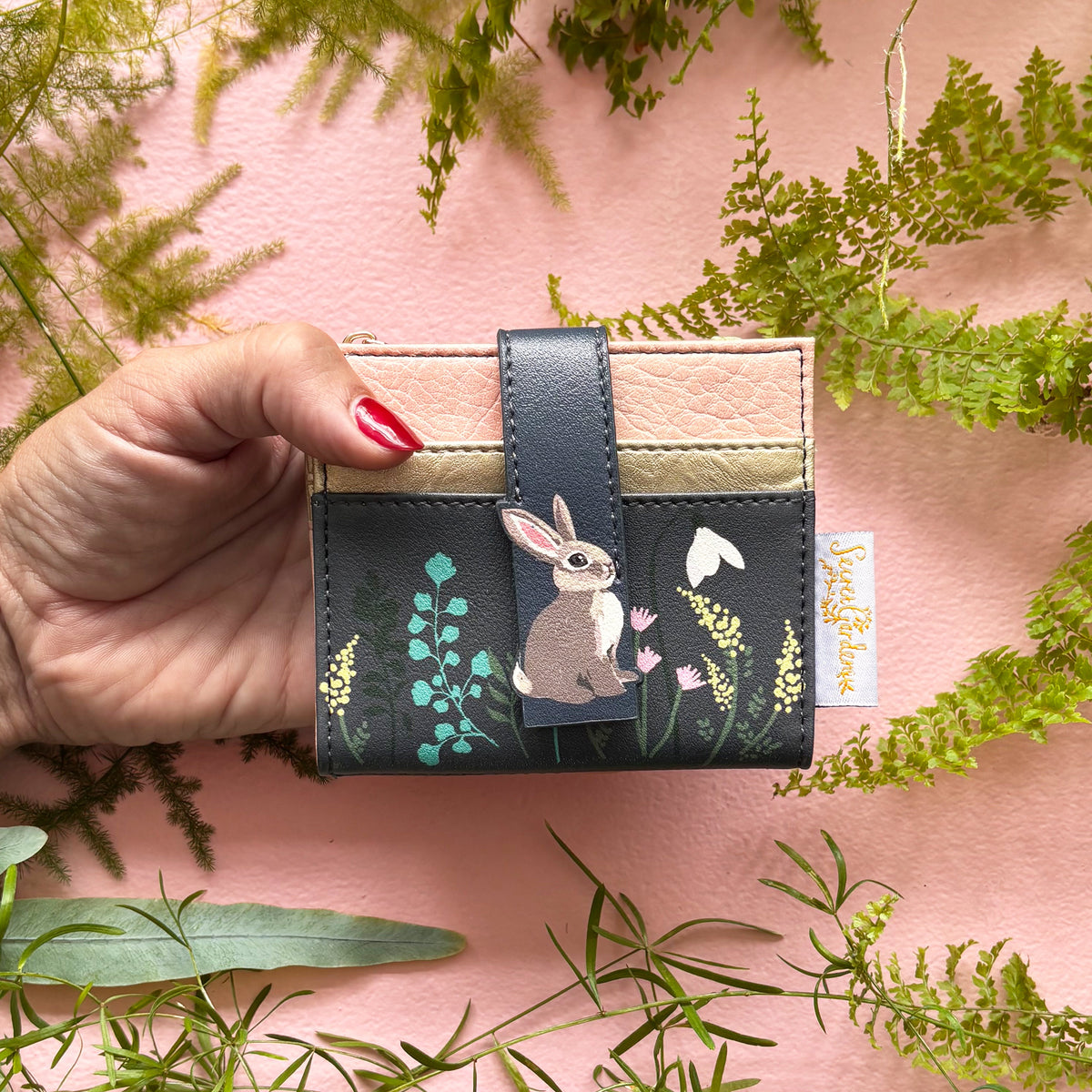 Secret Garden rabbit purse held in hand on pink background with ferns