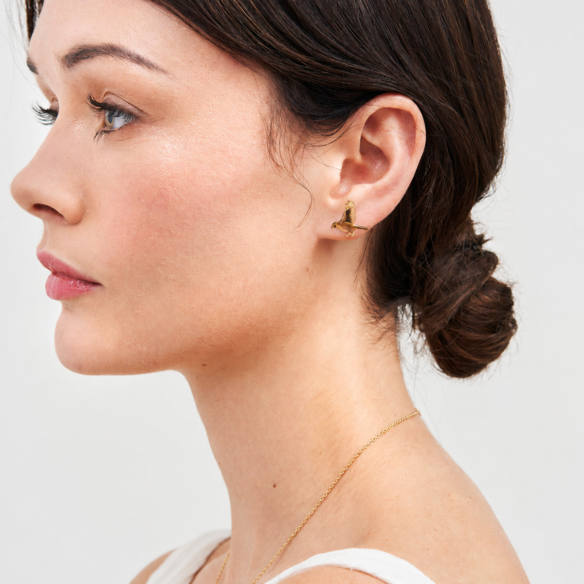 Flying robin stud earring worn by dark-haired model in profile