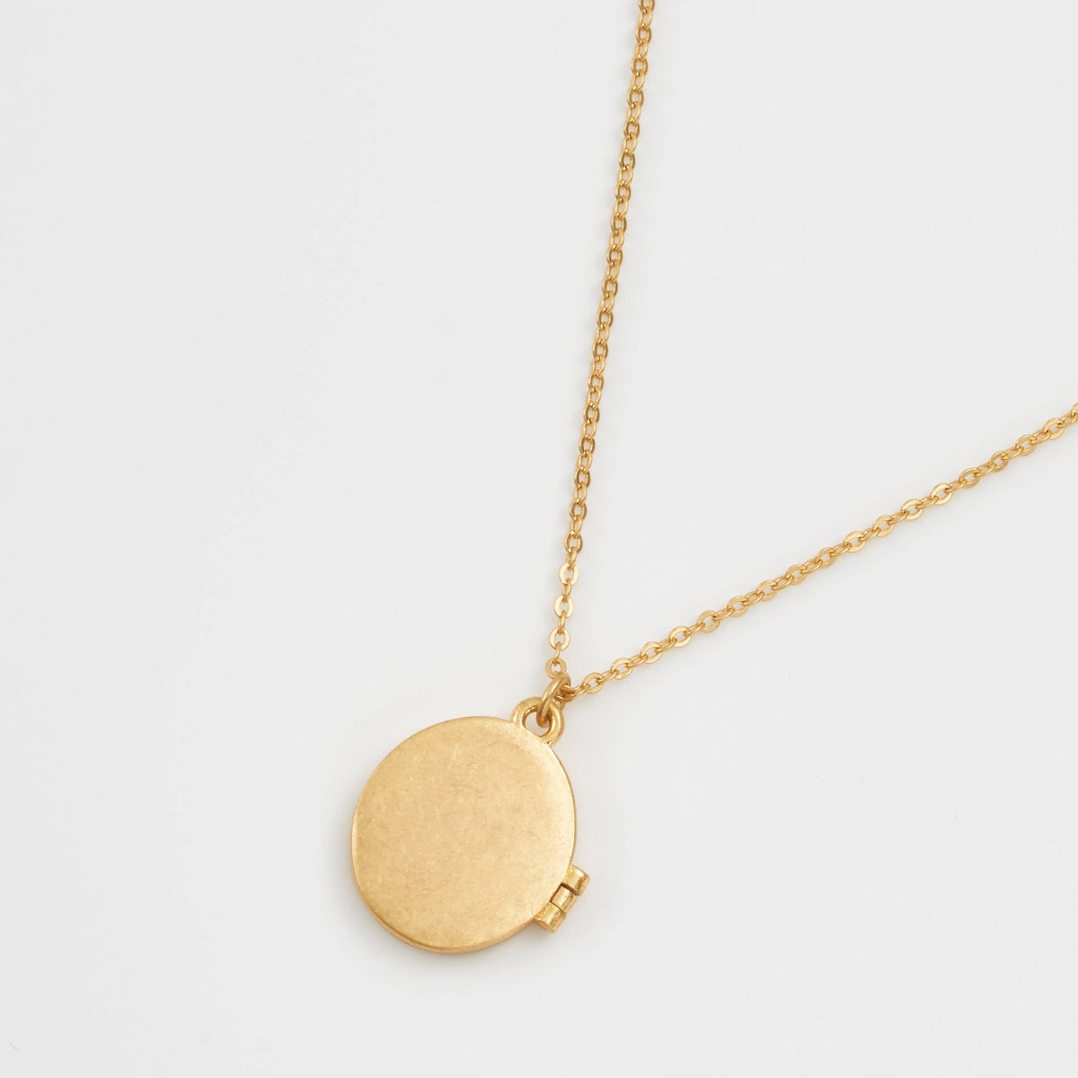 Gold locket necklace back view showing plain polished finish on white