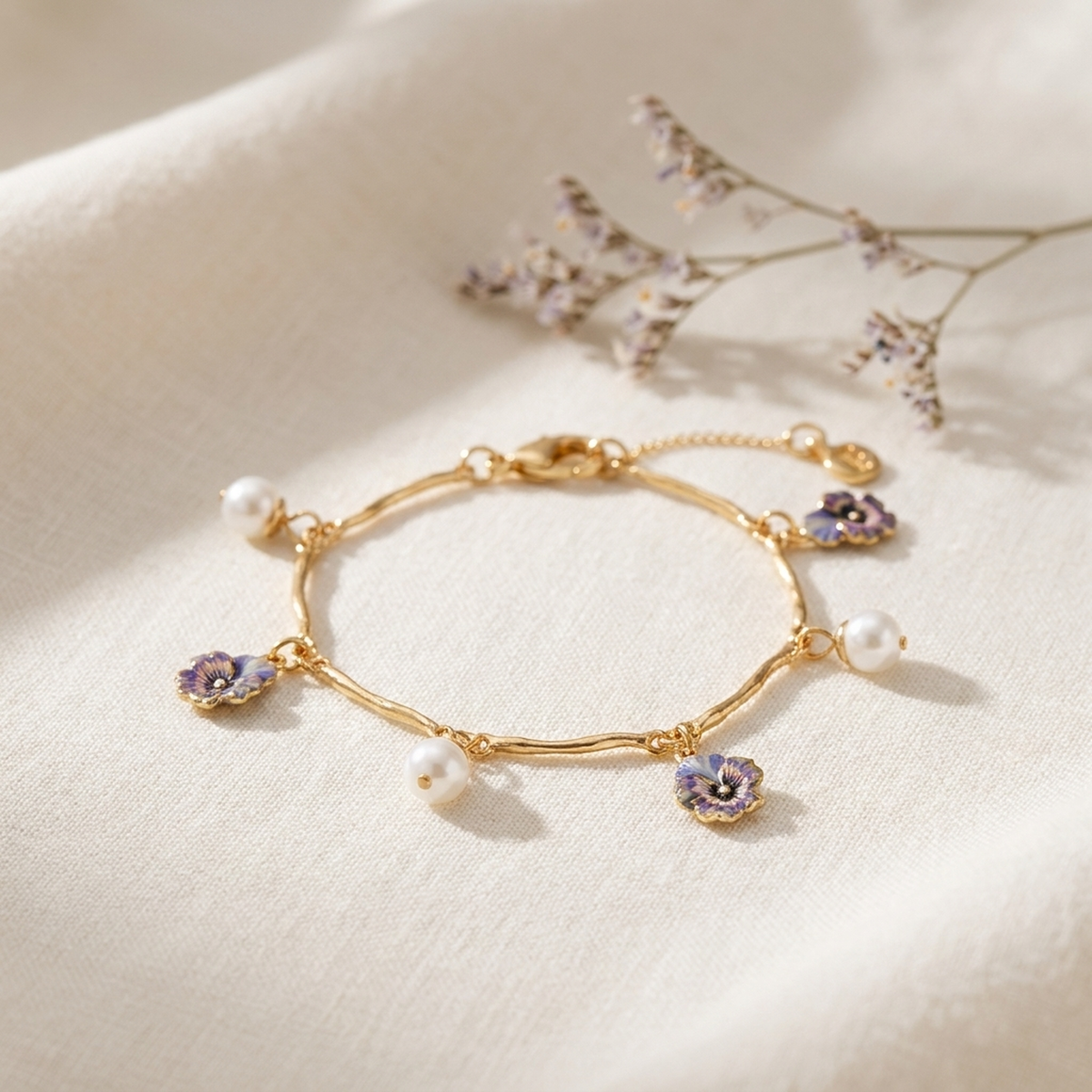 Pansy Pearl Gold Charm Bracelet styled on cream linen with dried flowers
