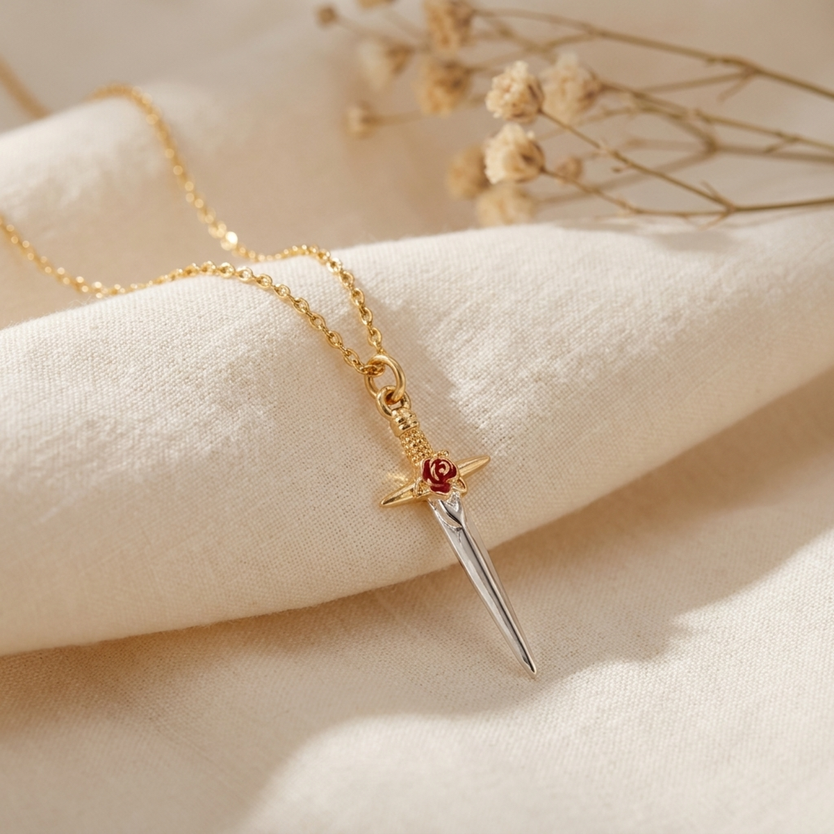 Rose Dagger Necklace draped on soft cream fabric with dried flowers