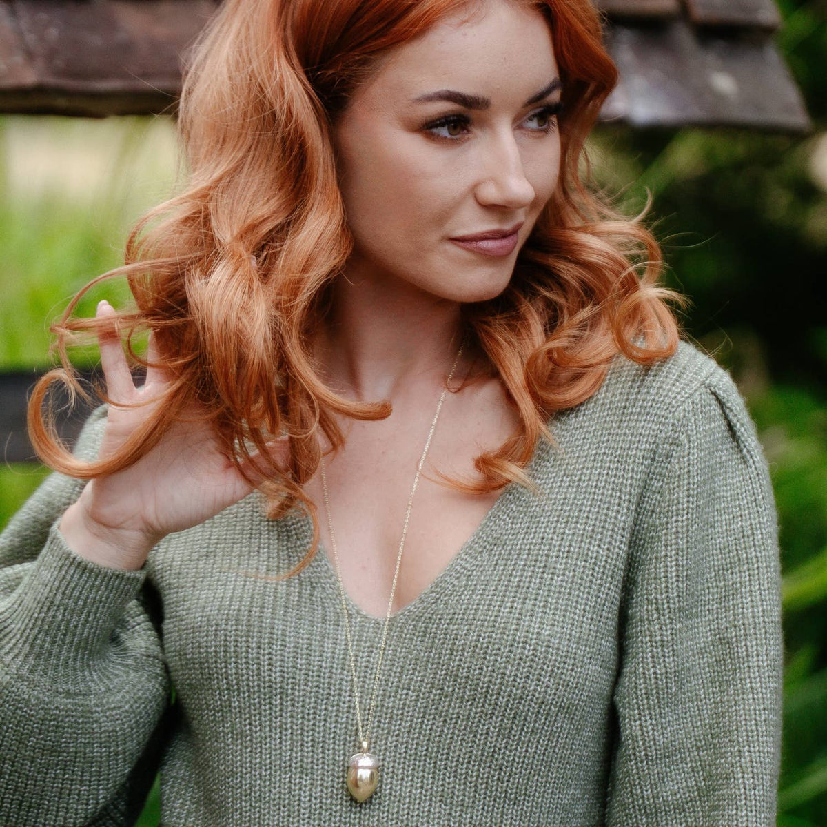 Model wearing Bill Skinner Squirrel Acorn Locket with green knit sweater, pendant resting at chest length.