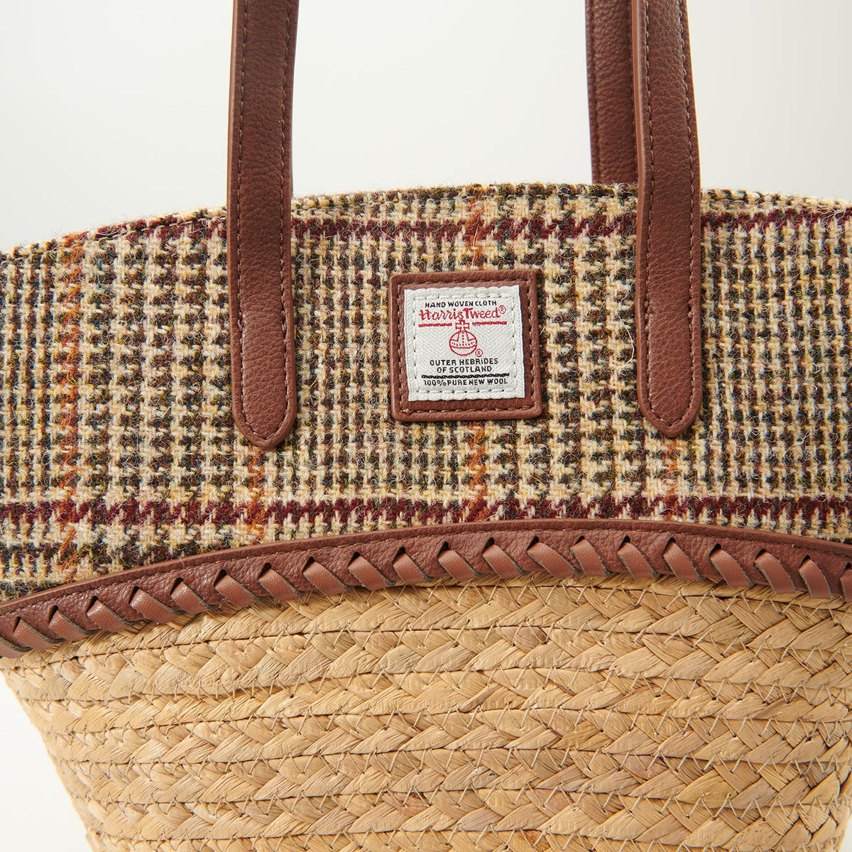 Close up of the dogtooth Harris Tweed lid, plaited leather trim and label