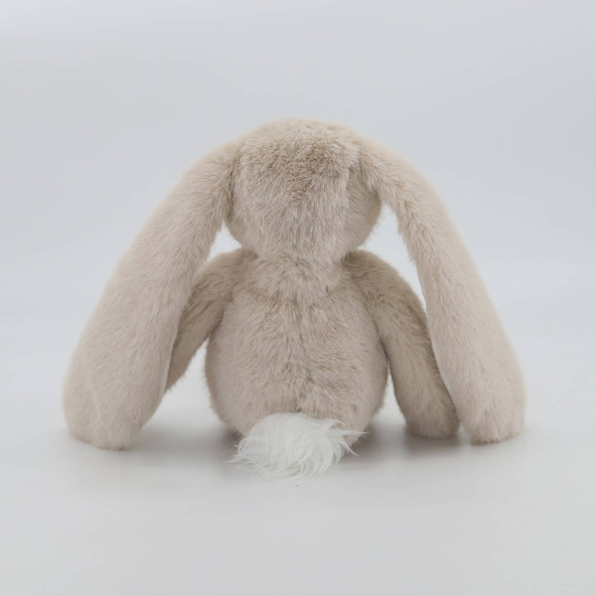 Back view of beige plush bunny showing fluffy white pom-pom tail
