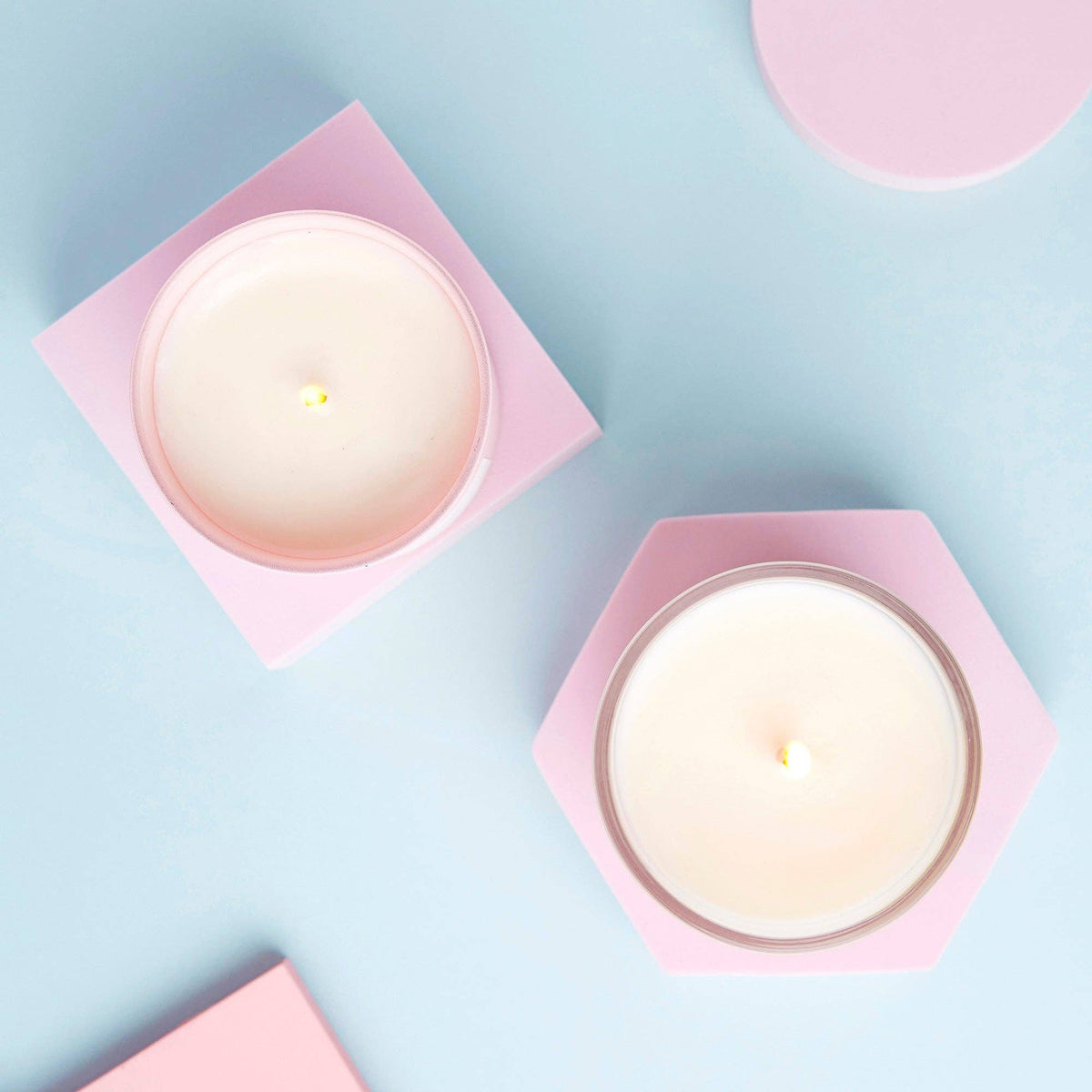 My Last Fuck candles seen from above in pink holders on a pale blue surface