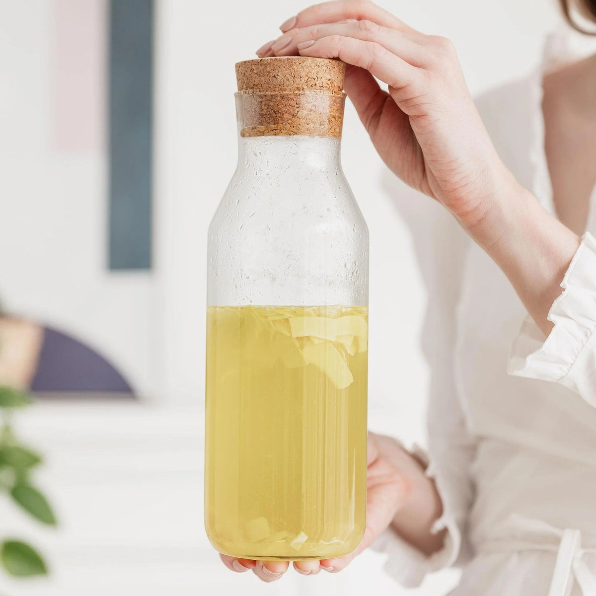 Infused Piña Colada rum mixture in a glass bottle with cork lid held in hand.