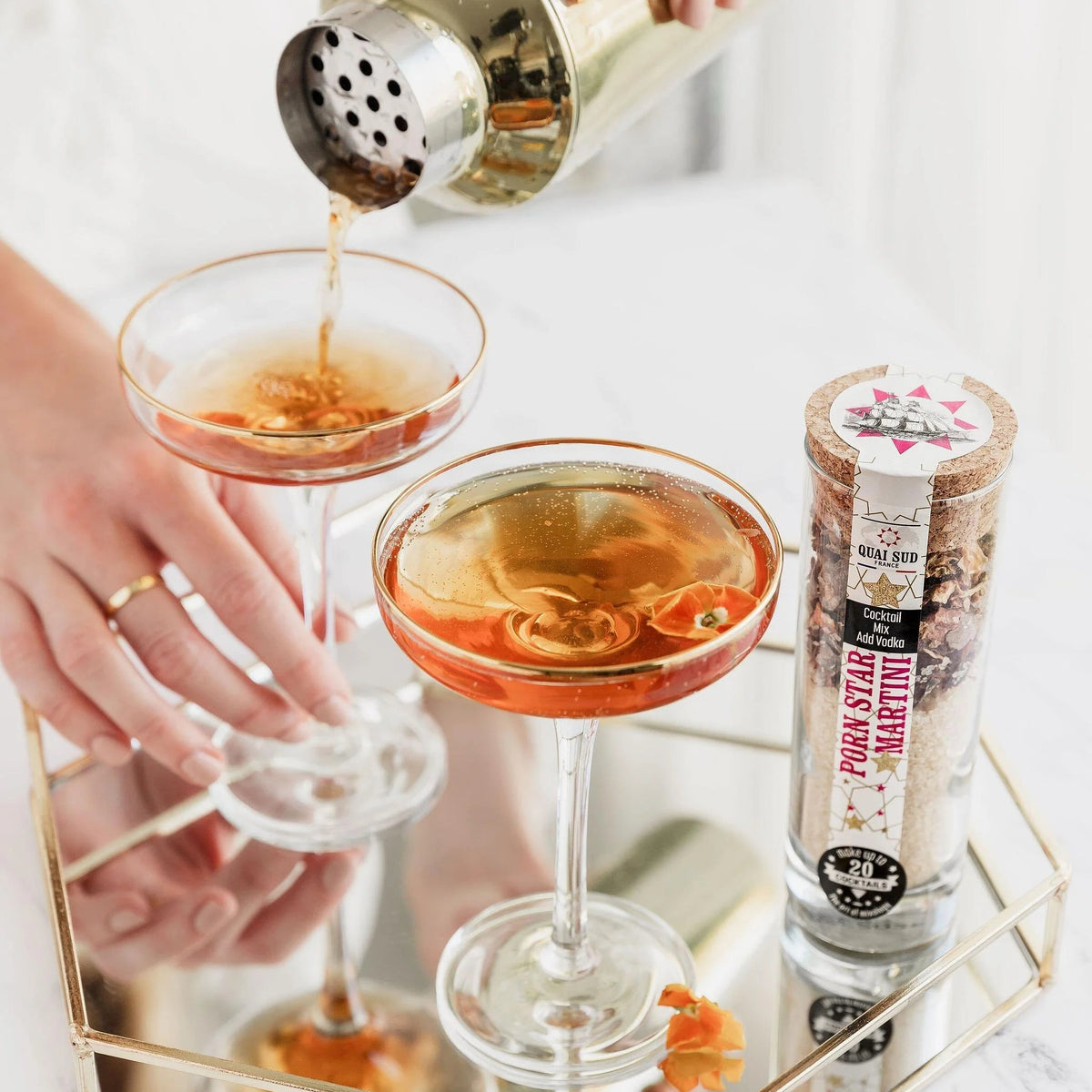 Pouring Porn Star Martini cocktail from shaker into coupe glasses.