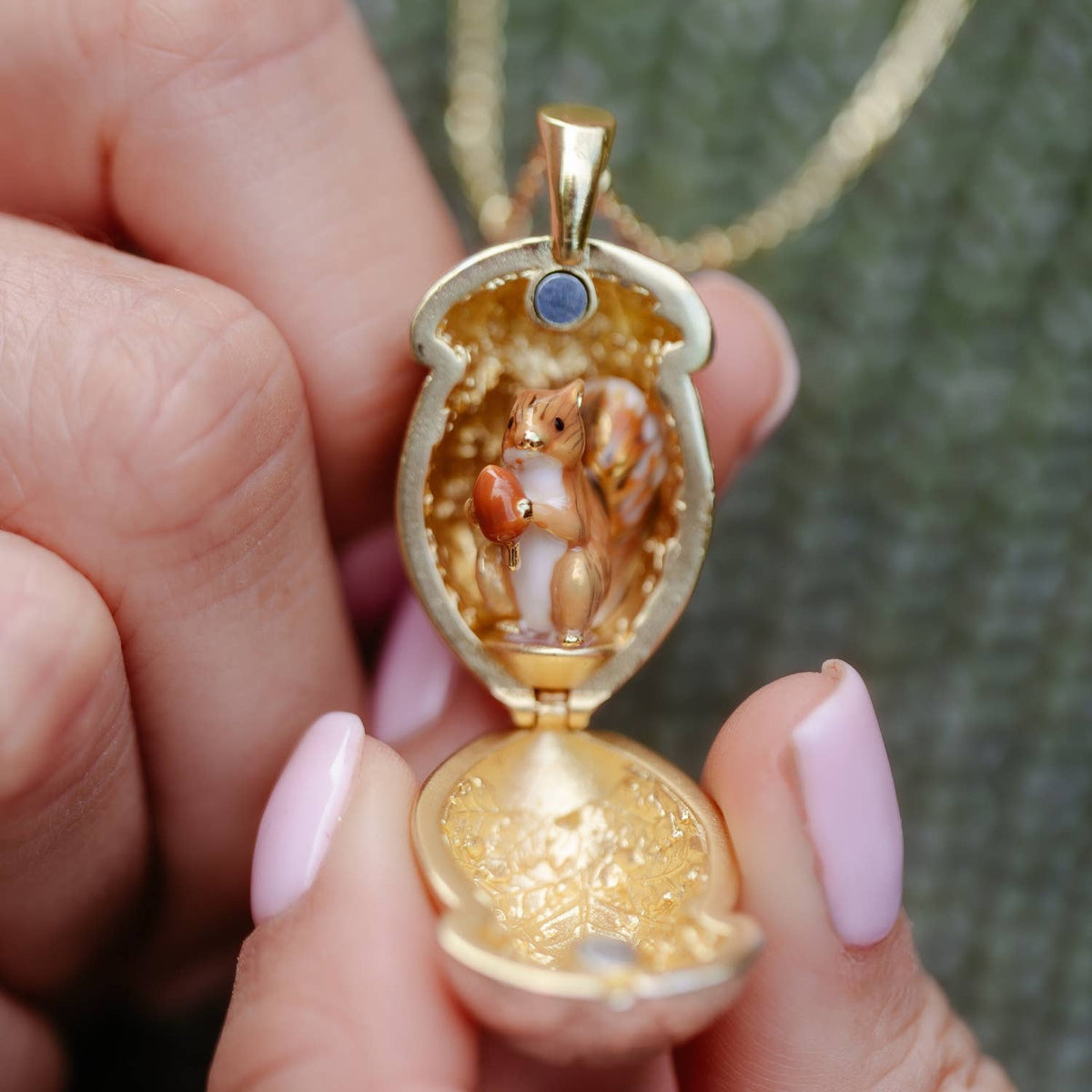 Close-up of Squirrel Acorn Locket open to reveal hand-painted enamel squirrel inside golden acorn pendant by Bill Skinner.